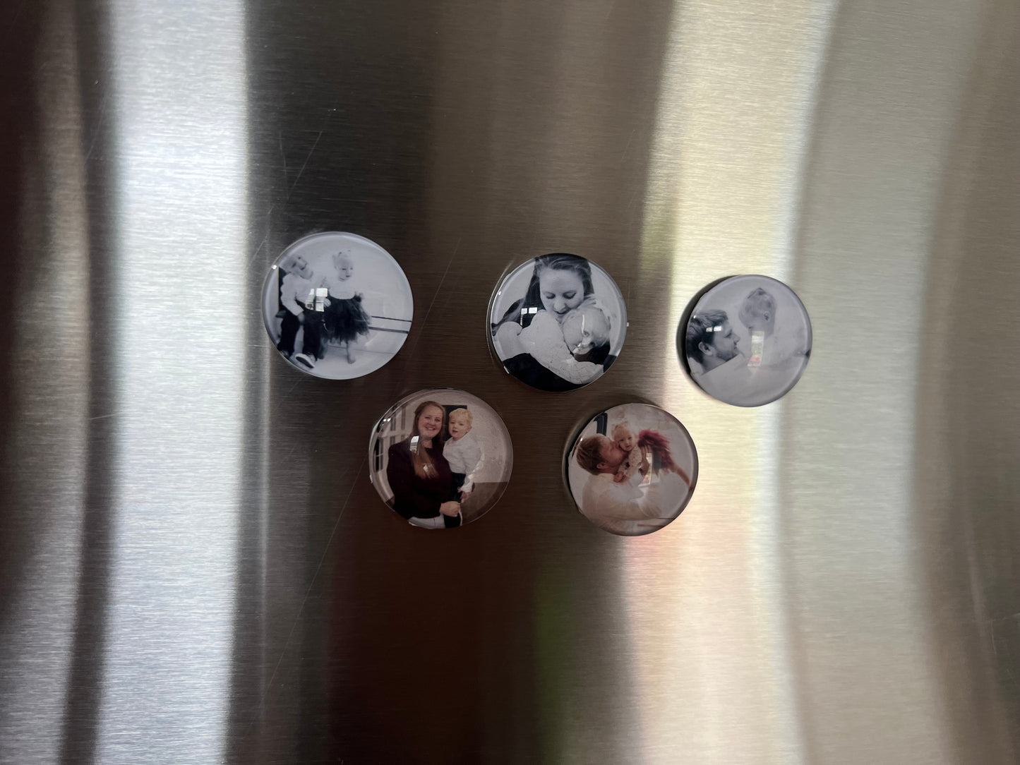 Five round photo magnets on a metallic surface
